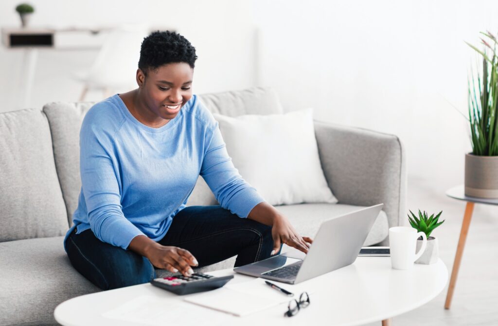 Black woman using calculator and laptop pc at home